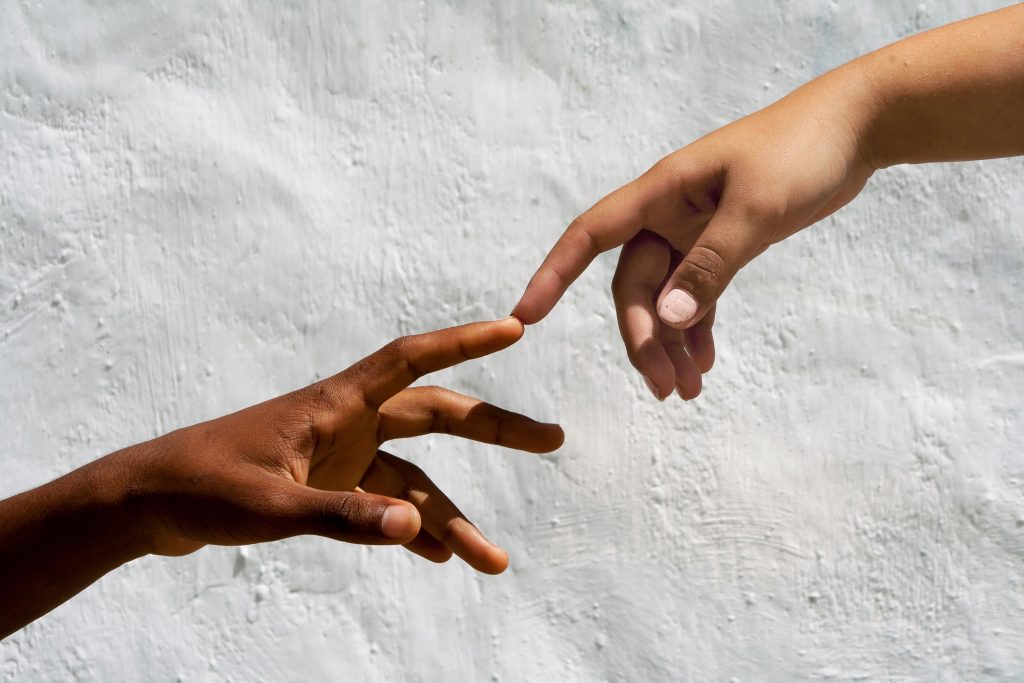Artistic depiction of human connection with two hands reaching against white backdrop.